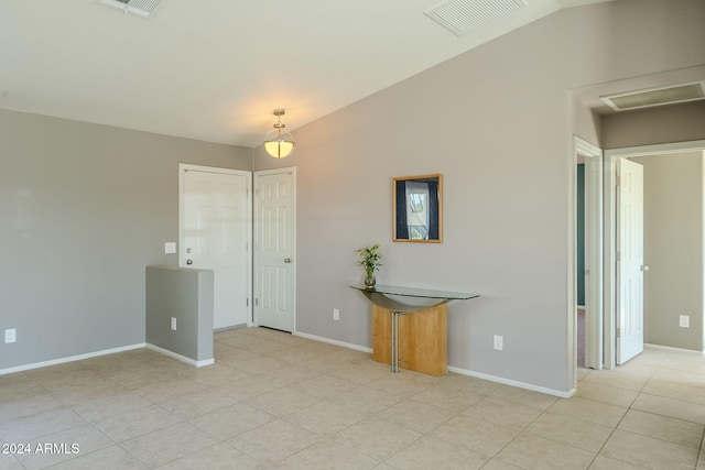 tiled empty room featuring vaulted ceiling