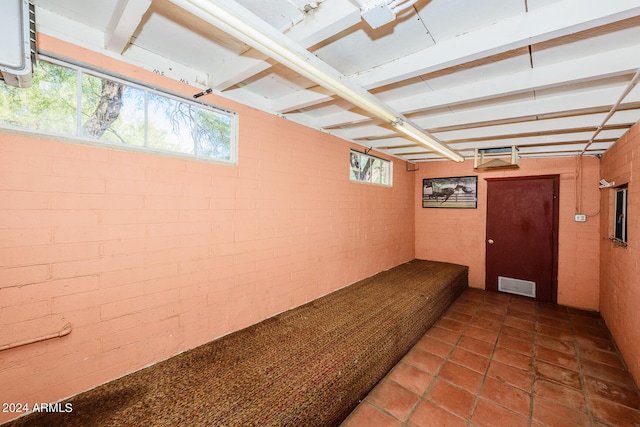 basement featuring tile patterned floors and brick wall