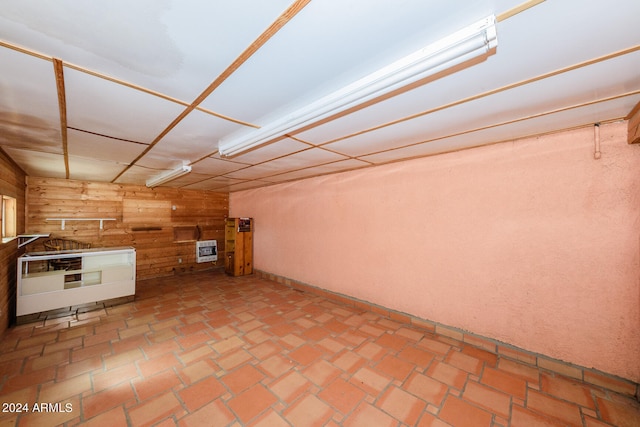 basement featuring wood walls and heating unit