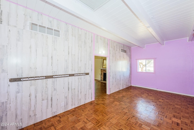 empty room with parquet floors, a fireplace, wood walls, and beam ceiling