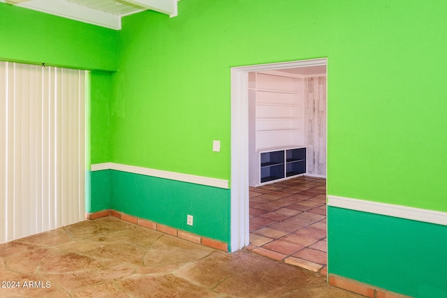 tiled empty room with beamed ceiling