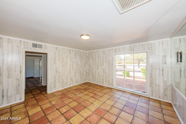 spare room featuring ornamental molding and wooden walls