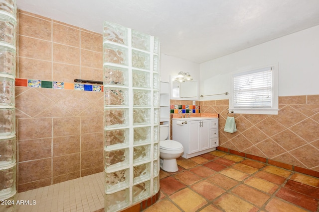 bathroom with vanity, a shower, toilet, and tile walls