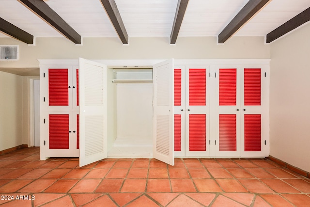 unfurnished bedroom featuring beamed ceiling and a closet