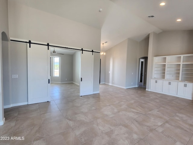 interior space with light tile flooring, ceiling fan, high vaulted ceiling, a barn door, and built in shelves