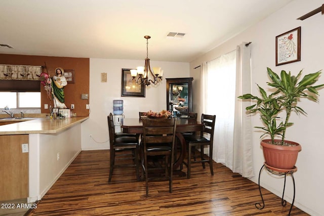 dining room featuring sink, a notable chandelier, and dark hardwood / wood-style flooring