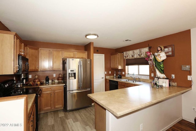 kitchen featuring kitchen peninsula, black appliances, and light wood-type flooring