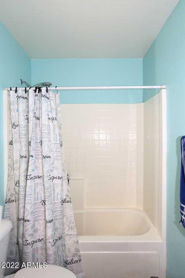 bathroom with shower / bath combination with curtain and toilet