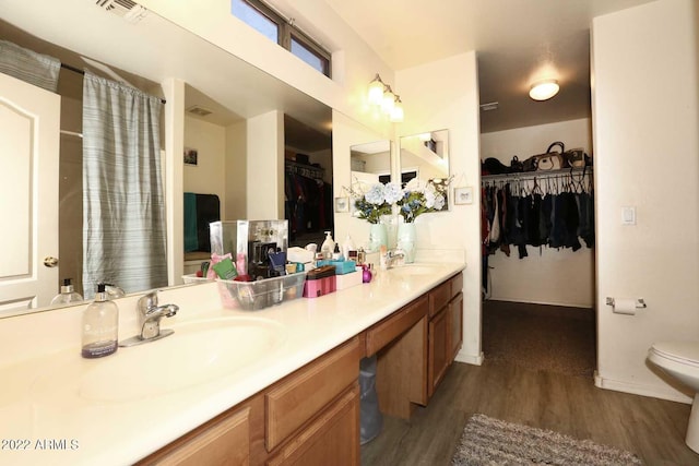 bathroom featuring hardwood / wood-style flooring, dual vanity, and toilet