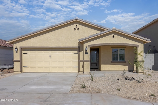 view of front facade featuring driveway, an attached garage, a tiled roof, and stucco siding