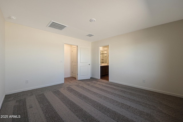 unfurnished bedroom with visible vents, dark carpet, and baseboards