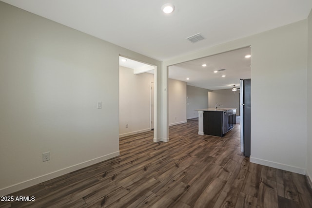 unfurnished living room with a sink, baseboards, dark wood-style flooring, and recessed lighting