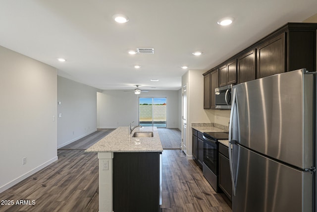 kitchen with a kitchen island with sink, dark wood-type flooring, a sink, visible vents, and appliances with stainless steel finishes