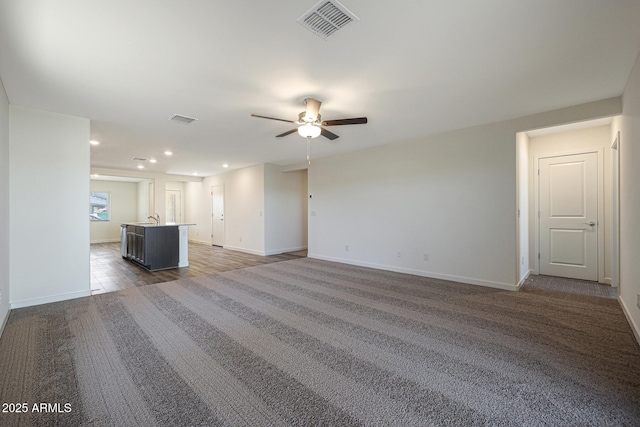 unfurnished living room with baseboards, visible vents, a ceiling fan, and recessed lighting