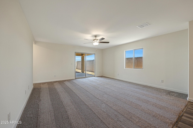 carpeted empty room featuring baseboards, visible vents, and ceiling fan