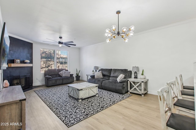 living room with a fireplace, ceiling fan with notable chandelier, crown molding, and light hardwood / wood-style flooring