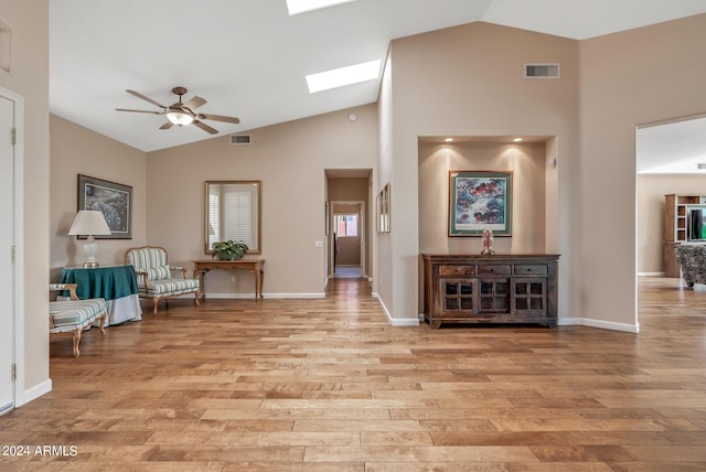 sitting room featuring high vaulted ceiling, light hardwood / wood-style flooring, ceiling fan, and a skylight