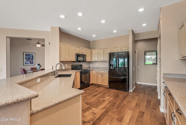 kitchen with sink, light stone counters, black appliances, light hardwood / wood-style floors, and kitchen peninsula