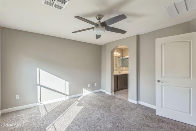 unfurnished bedroom with ceiling fan, light carpet, and connected bathroom