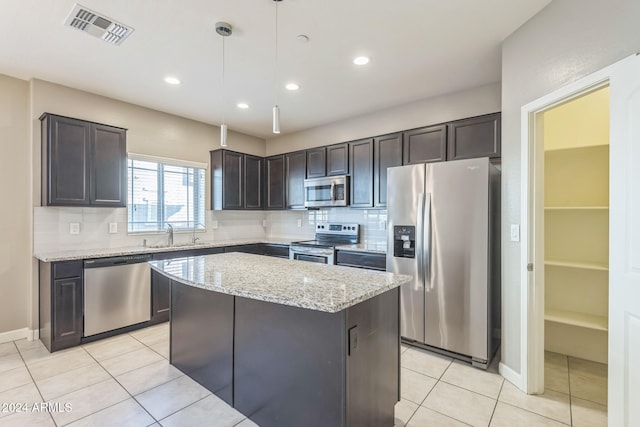 kitchen with light stone counters, dark brown cabinets, stainless steel appliances, decorative light fixtures, and a kitchen island