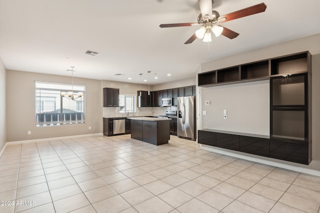 kitchen featuring ceiling fan with notable chandelier, hanging light fixtures, light tile patterned floors, a kitchen island, and stainless steel appliances