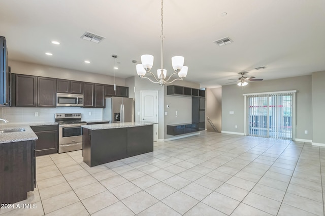 kitchen featuring tasteful backsplash, ceiling fan with notable chandelier, stainless steel appliances, a center island, and hanging light fixtures