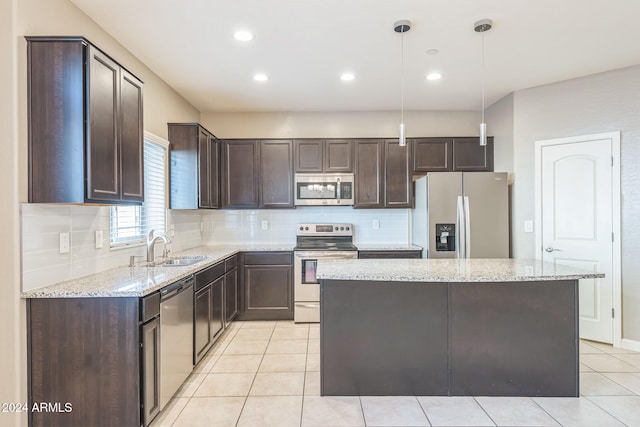 kitchen with backsplash, appliances with stainless steel finishes, decorative light fixtures, a kitchen island, and dark brown cabinetry