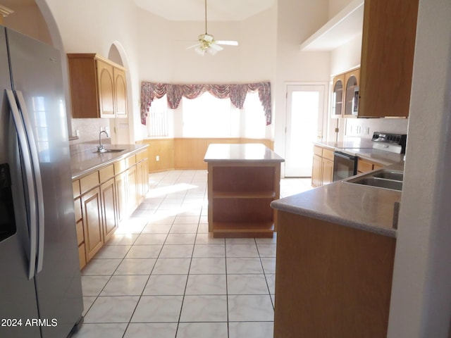 kitchen featuring appliances with stainless steel finishes, light tile patterned floors, a kitchen island, and sink