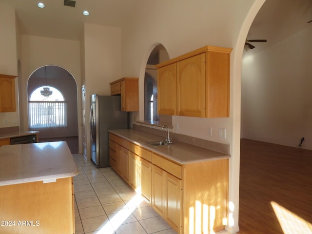 kitchen featuring stainless steel refrigerator, ceiling fan, sink, light brown cabinets, and light tile patterned floors