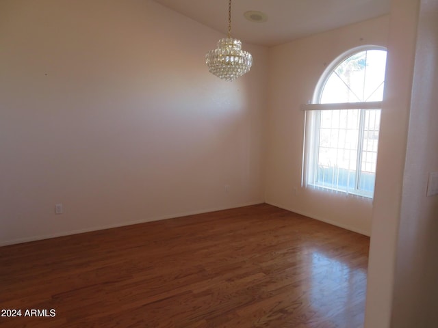 empty room featuring dark wood-type flooring and a notable chandelier