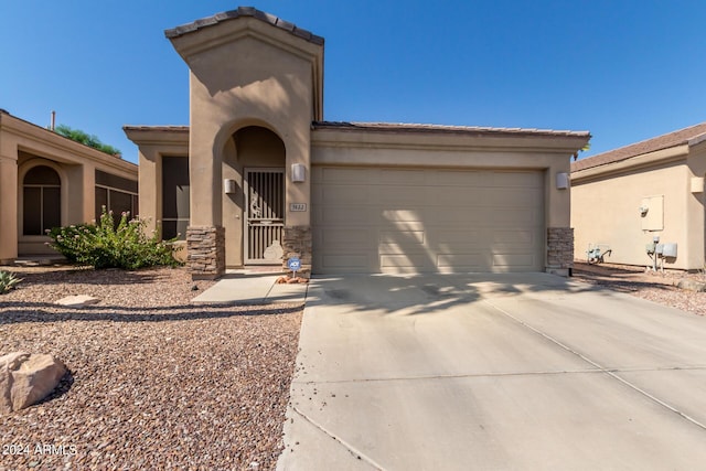 view of front of property featuring an attached garage, stucco siding, concrete driveway, stone siding, and a tile roof