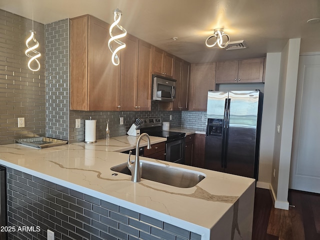 kitchen featuring sink, stainless steel appliances, light stone counters, decorative backsplash, and kitchen peninsula