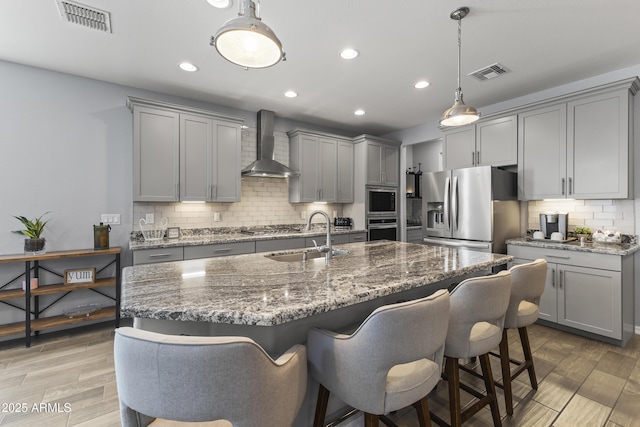 18865 W Mescal St, Surprise, AZ 85388 - kitchen with gray cabinets, stainless steel appliances, wall chimney range hood, a breakfast bar, and recessed lighting