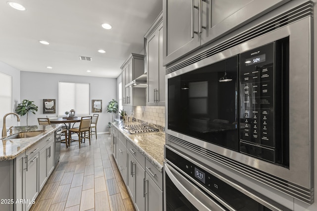 18865 W Mescal St, Surprise, AZ 85388 - kitchen with gray cabinets, appliances with stainless steel finishes, decorative backsplash, light stone countertops, and recessed lighting