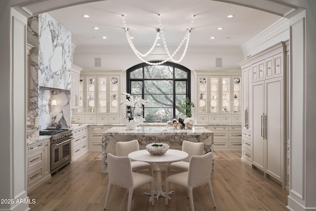 kitchen with white cabinetry, a center island, a kitchen breakfast bar, light stone countertops, and range with two ovens