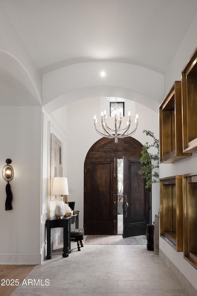 entrance foyer with lofted ceiling, a chandelier, and light hardwood / wood-style floors