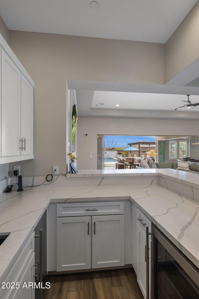 kitchen featuring beverage cooler, white cabinetry, and light stone countertops