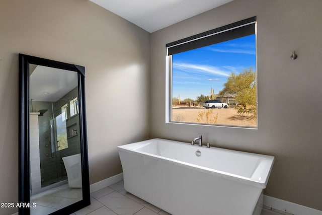 bathroom with a stall shower, baseboards, and a freestanding tub