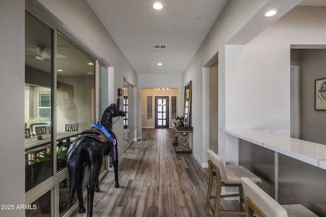 hallway with visible vents, recessed lighting, baseboards, and wood finished floors