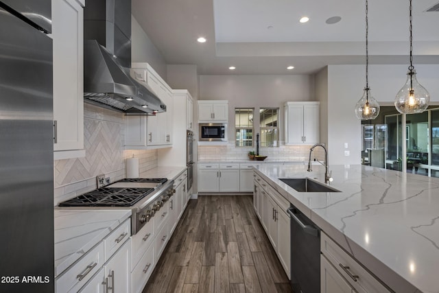 kitchen with white cabinets, wall chimney exhaust hood, stainless steel appliances, and a sink