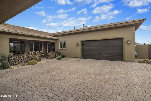 view of front facade with stucco siding, decorative driveway, and a garage