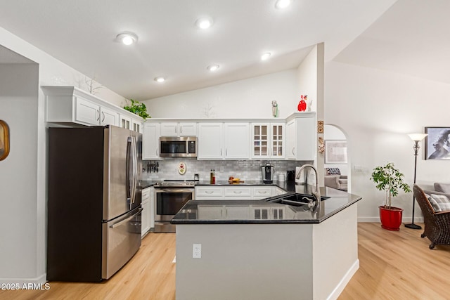 6017 E Kathleen Rd, Scottsdale, AZ 85254 - kitchen featuring appliances with stainless steel finishes, light wood-style floors, a peninsula, lofted ceiling, and decorative backsplash
