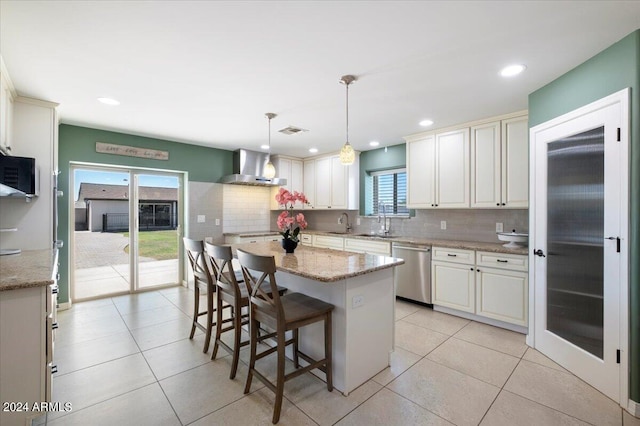 kitchen featuring wall chimney exhaust hood, hanging light fixtures, stainless steel dishwasher, and a healthy amount of sunlight