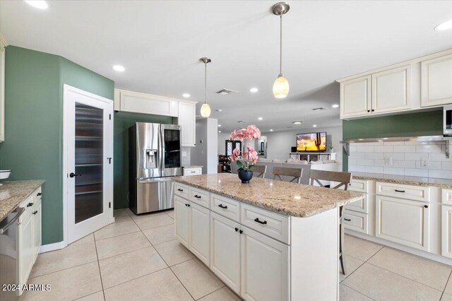 kitchen with a kitchen island, stainless steel appliances, tasteful backsplash, hanging light fixtures, and a kitchen bar