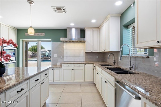 kitchen featuring light stone counters, pendant lighting, wall chimney range hood, and stainless steel dishwasher