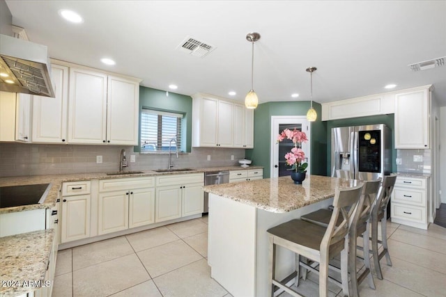 kitchen featuring stainless steel appliances, hanging light fixtures, sink, and wall chimney range hood