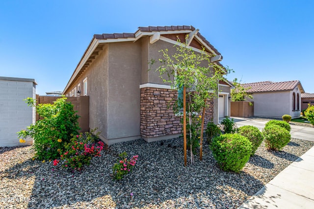 4077 S Quinn Ave, Gilbert, AZ 85297 - view of front of house featuring fence, an attached garage, a tile roof, stone siding, and stucco siding
