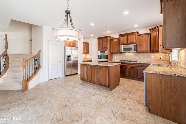 kitchen with stainless steel appliances, a sink, light stone countertops, a kitchen island, and recessed lighting