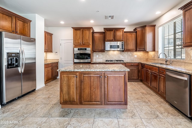 kitchen featuring stainless steel appliances, a sink, a center island, tasteful backsplash, and recessed lighting