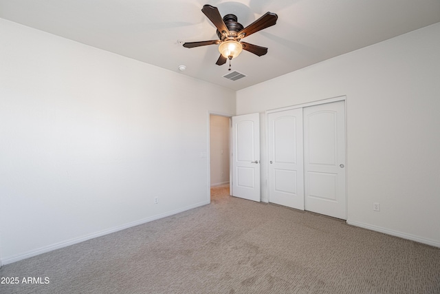 unfurnished bedroom featuring carpet floors, a closet, baseboards, and a ceiling fan